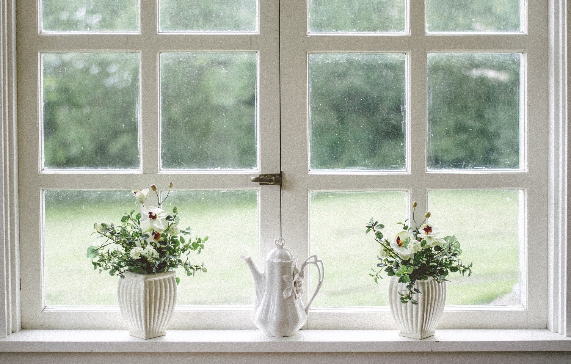 white flowers pots and a white teapot in front of a white window frame
